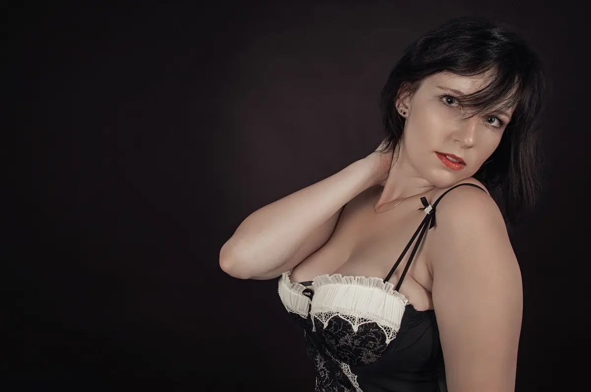 Mature brunette woman posed against a dark studio background